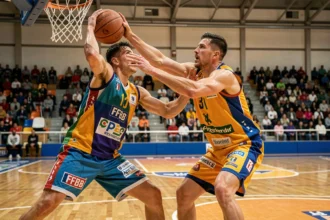 Deux joueurs de basket en duel sous le panier lors d'un match officiel FFBB en salle