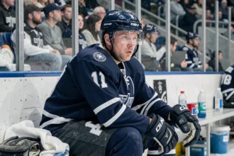 Joueur de hockey sur glace assis sur le banc pendant une pause entre deux périodes, en tenue complète, dans une patinoire professionnelle
