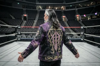 Catcheur chevronné de dos face au ring d'un immense arena vide, veste gothique noire et violette, atmosphère dramatique et introspective évoquant le renouveau dans le catch professionnel